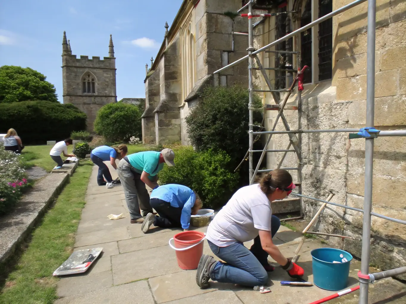 A team of volunteers restoring a war monument with tools and preservation materials, highlighting the dedication to preserving historical sites.